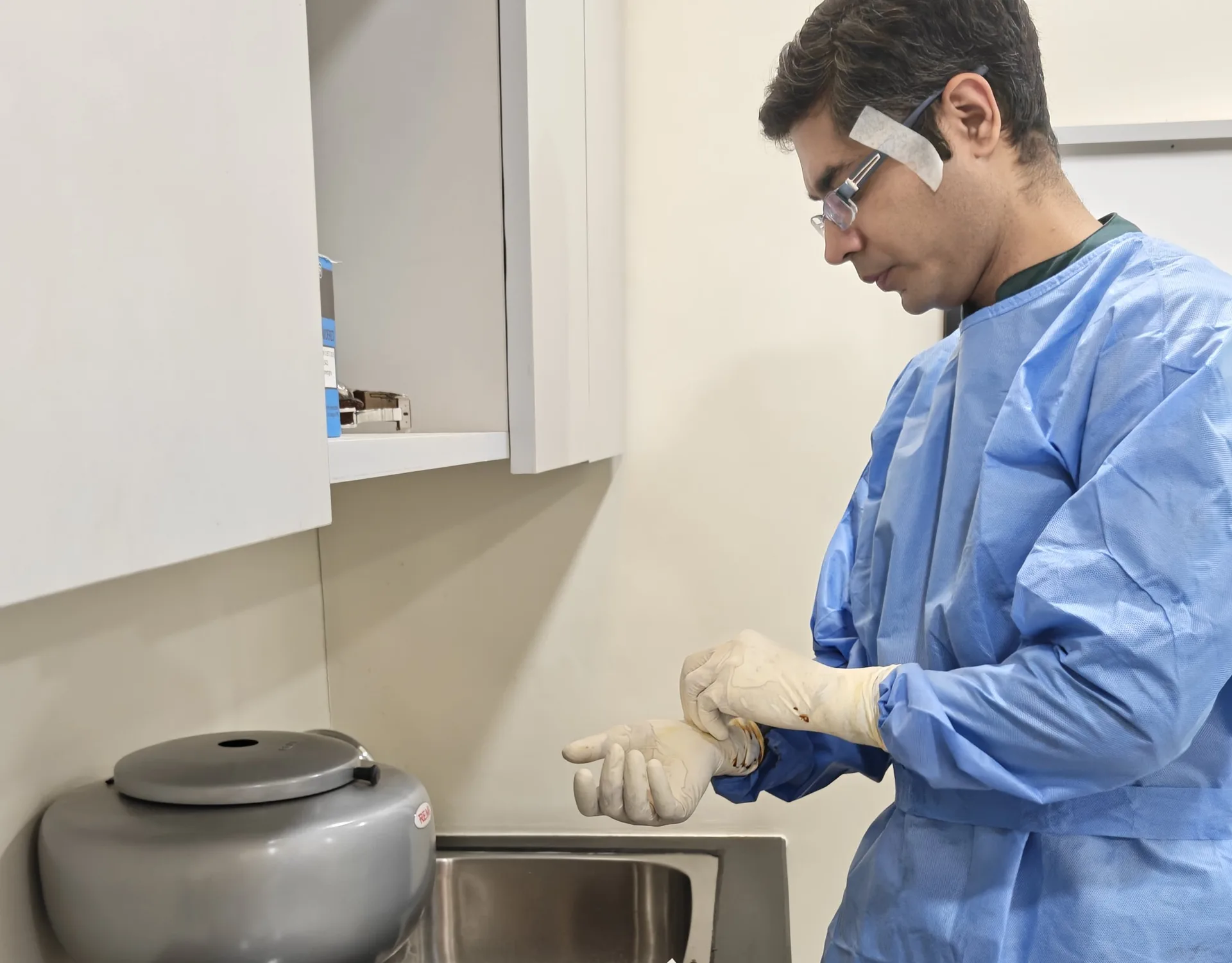Clinician in a sterile gown preparing an injection in the OSSO procedure room