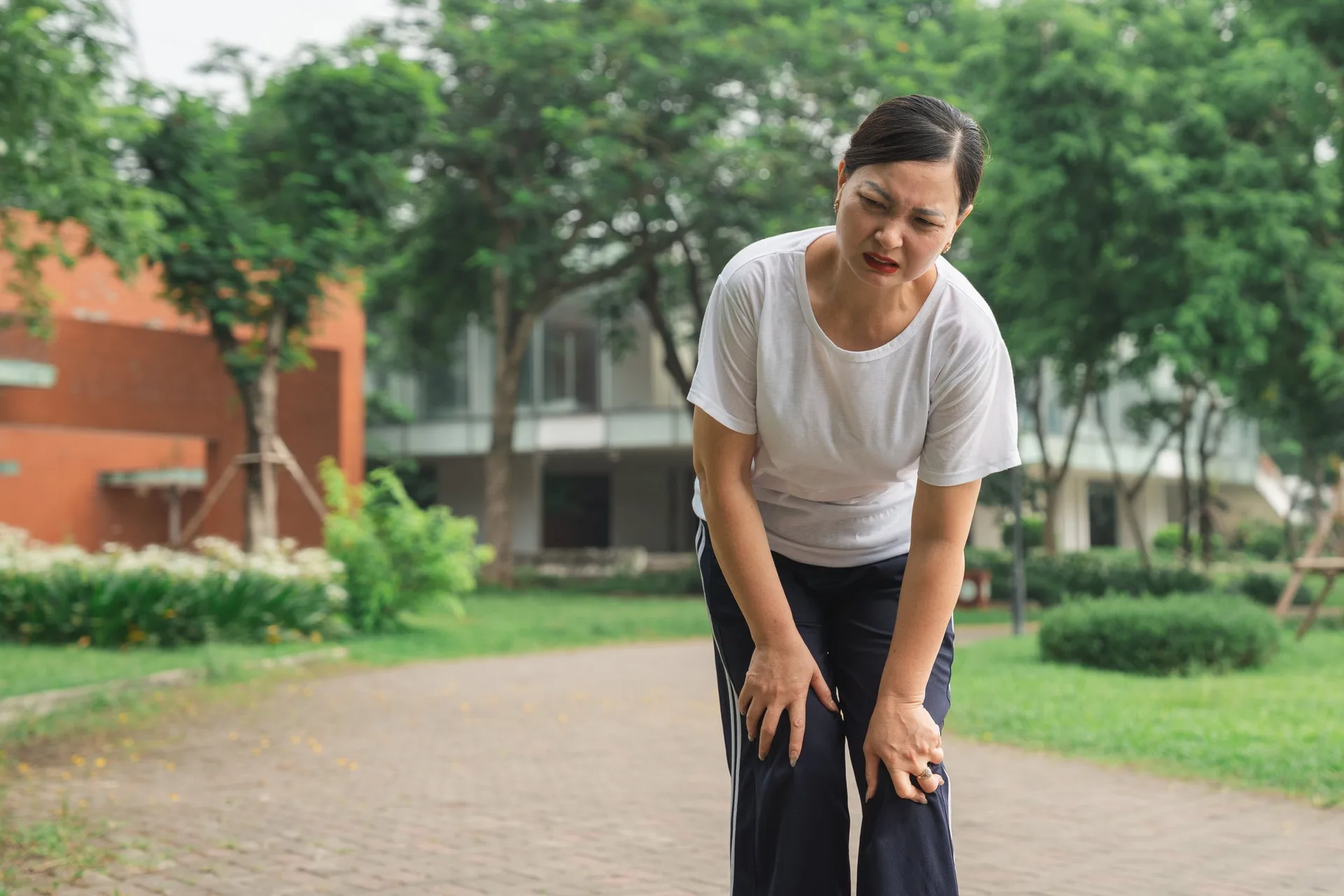 Woman pausing on a walk, holding her knee in discomfort