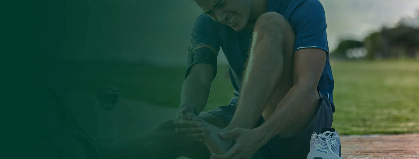 An athlete tending to an ankle injury beside a playing field
